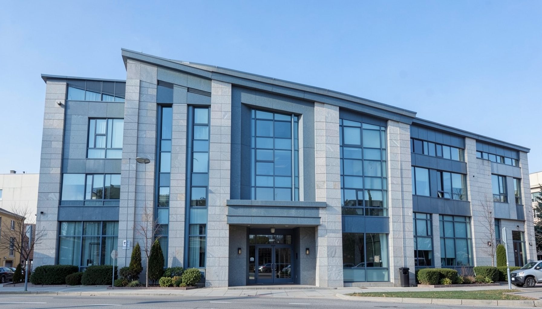 A calm office building facade in muted blue and stone tones under a clear sky, conveying an official diplomatic setting
