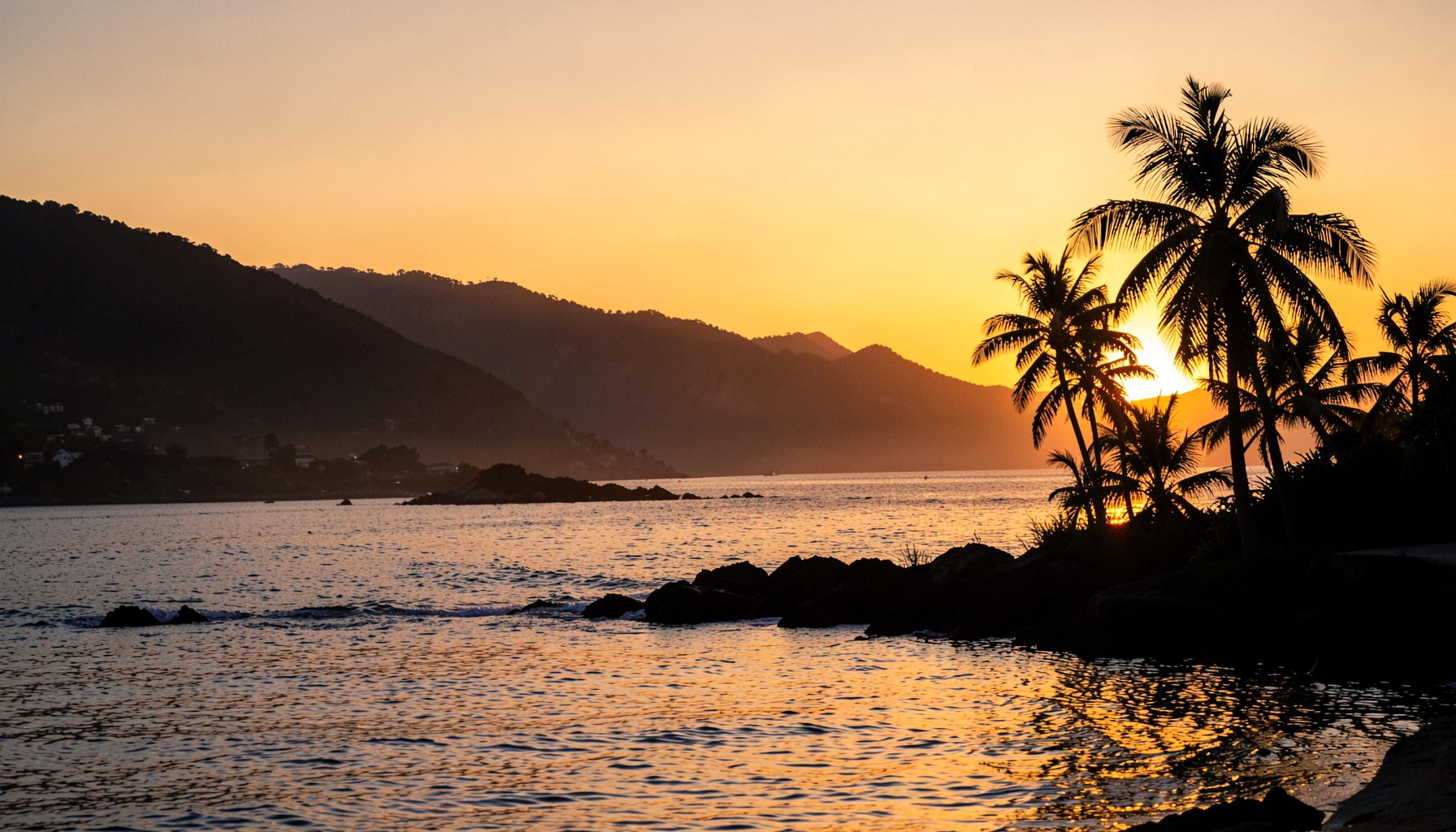 Warm sunset light over a coastal Ecuadorian scene with calm water and silhouetted palm trees, relaxed cinematic mood