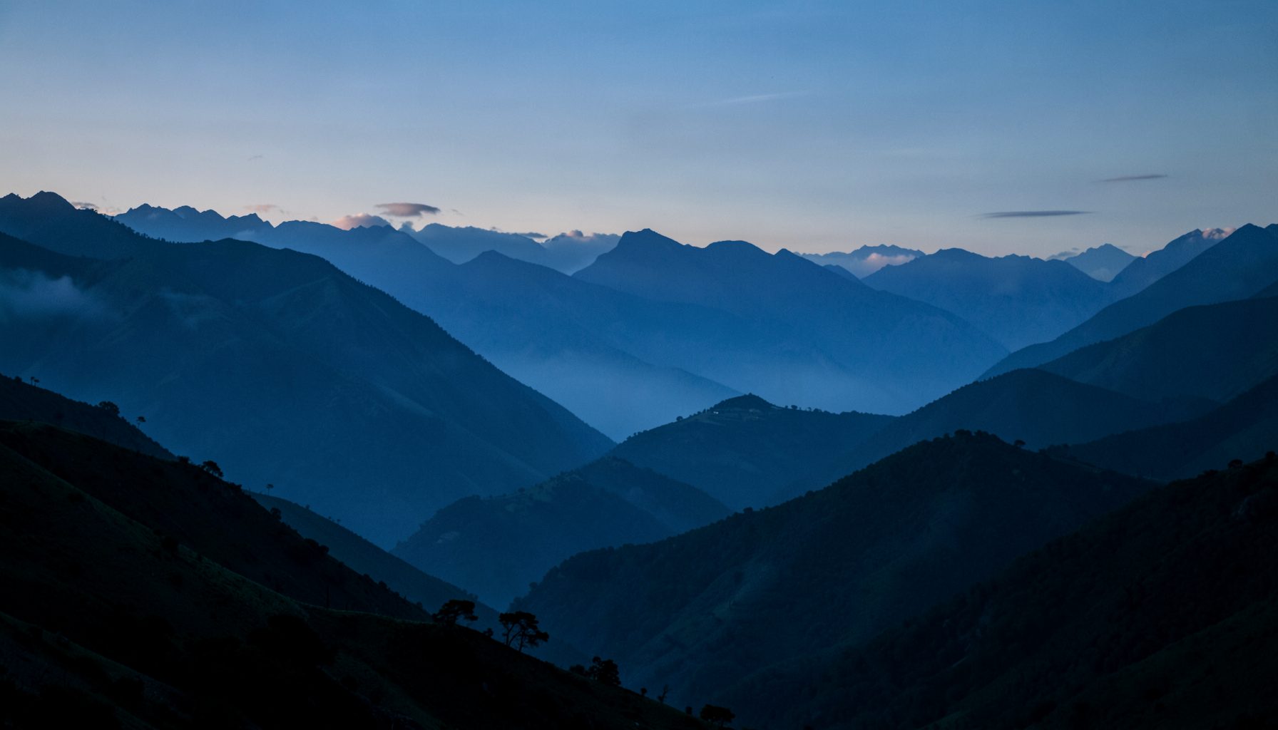 Andean mountain landscape at dusk with deep blue and green tones, layered ridgelines fading into soft mist, evoking a calm historical mood