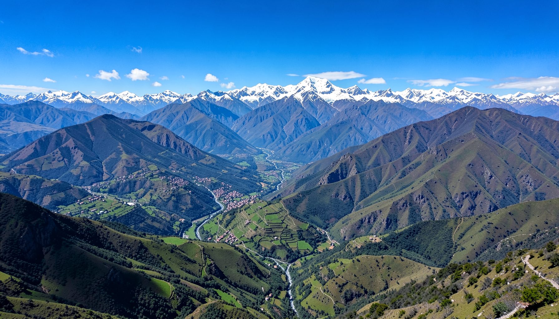 A sweeping aerial view of the Andes mountains in Ecuador, with green valleys and snow-capped peaks under a bright blue sky, conveying the dramatic geography of the country